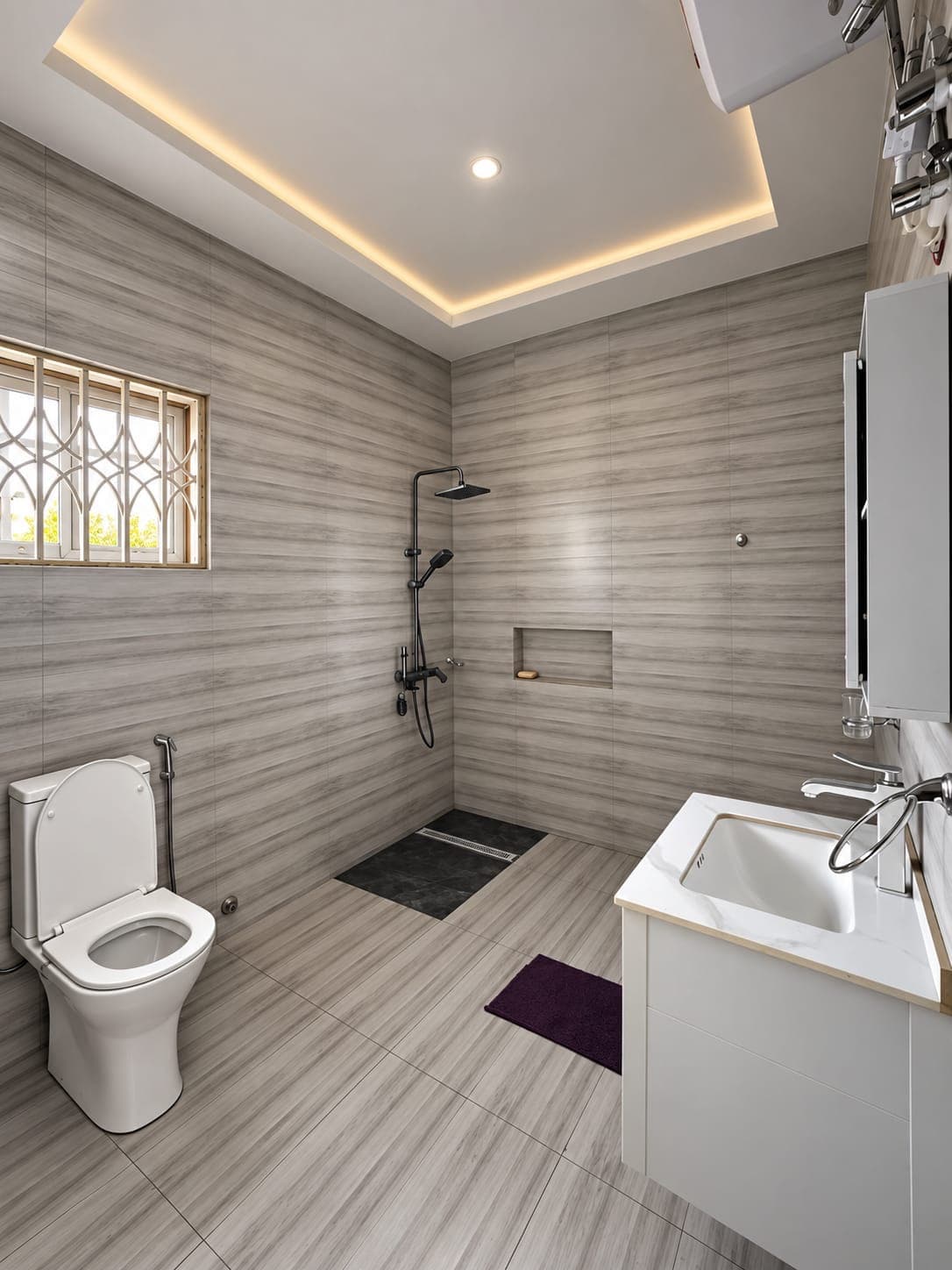 An en-suite bathroom with a walk-in rain shower, wood-effect grey tiles, a floating vanity and a lit ceiling cove