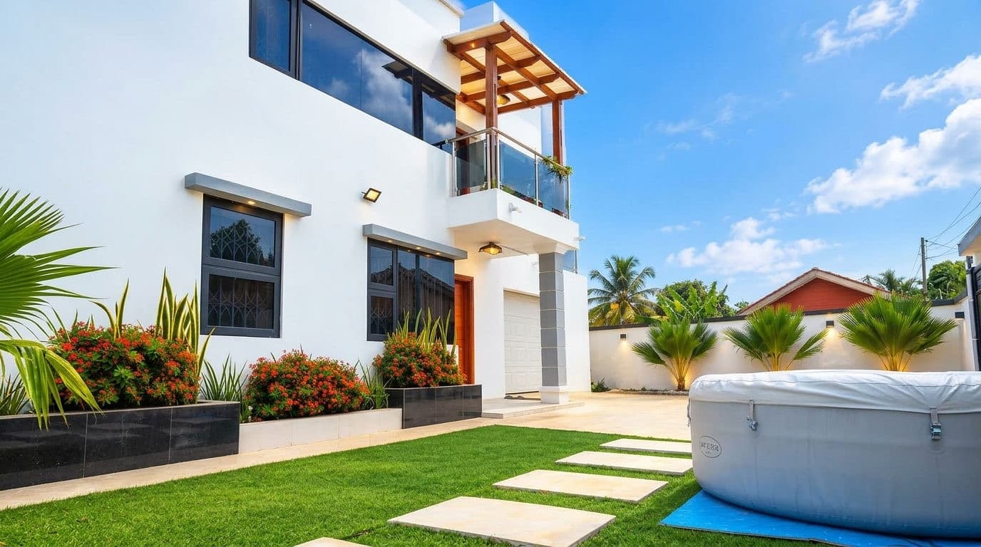 A wide view of the Baobab Nook facade, glass balcony and landscaped lawn, with palms lining the boundary wall